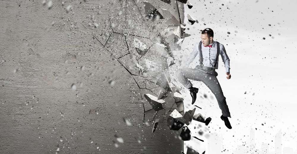 Emotional businessman breaking stone wall with karate punch